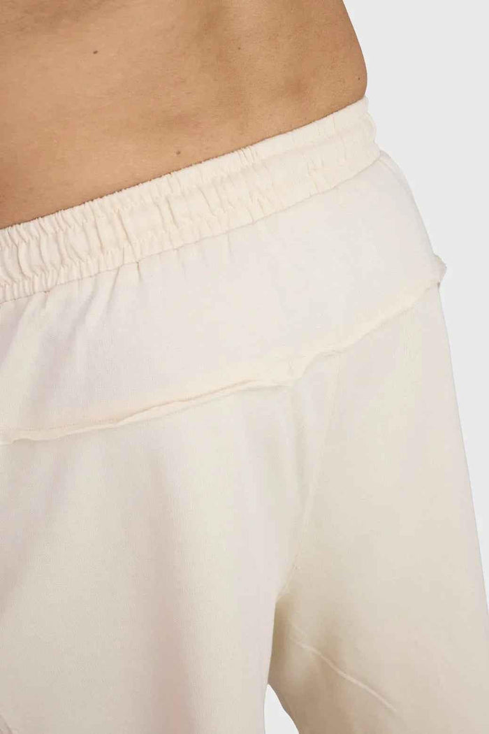 Beige raw edge oversized shorts by Fuaark Nz with relaxed fit and casual style, shown hanging on a clothing rack.