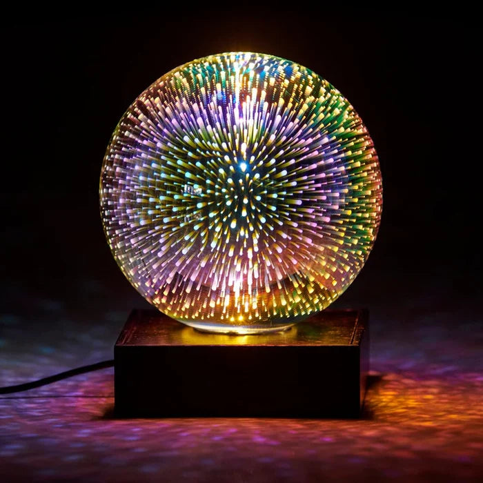 Spherical glass lamp on a black base with a 3D multi-colored starburst light effect glowing from the center.