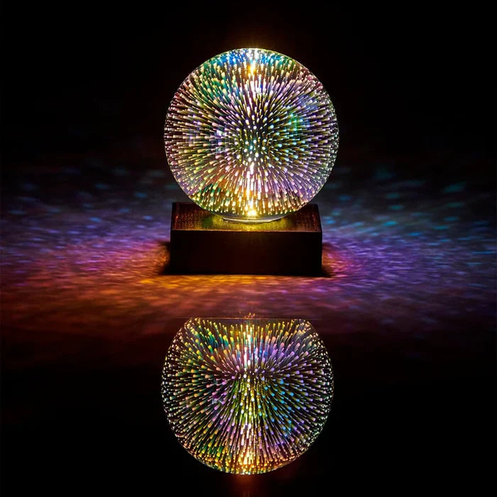 Spherical light with colorful firework patterns on a wooden base, reflecting on a dark surface.