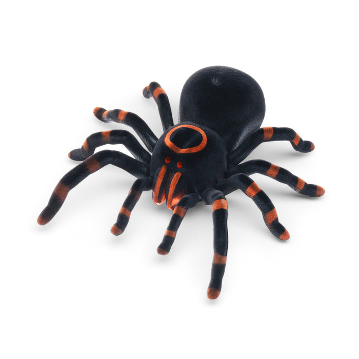 Fuzzy black tarantula toy with orange striped legs and an orange ring on its head, on a white background.