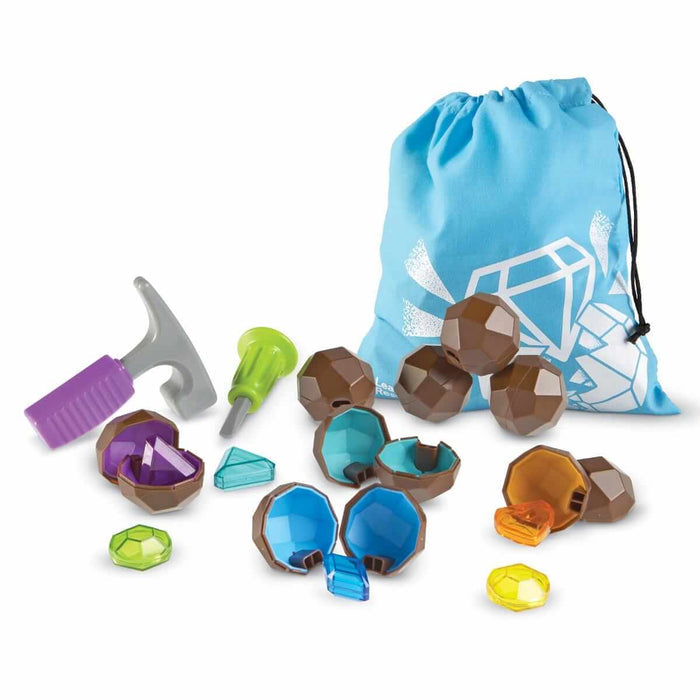 Brown toy geodes open to reveal colorful gems, plus a plastic hammer, chisel, and blue drawstring storage bag.