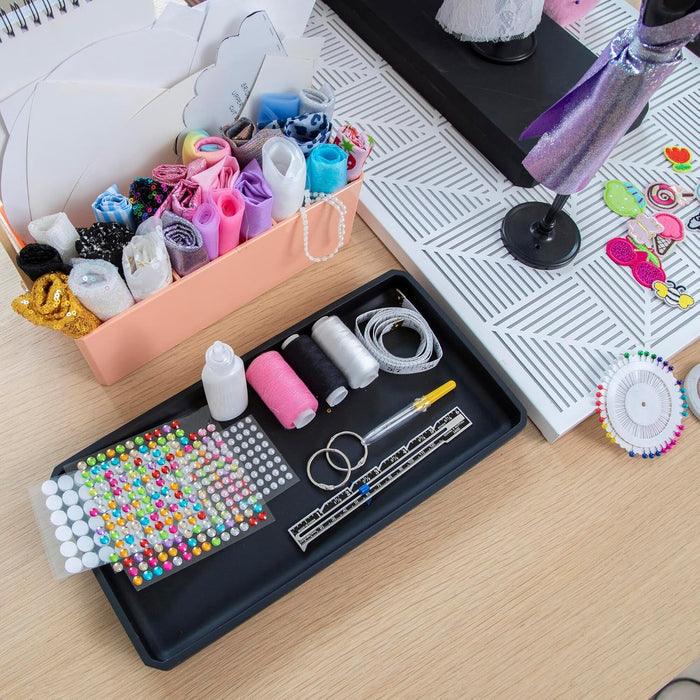 Fashion design kit with colorful fabrics, sewing tools, rhinestones, and a mannequin dressed in purple.