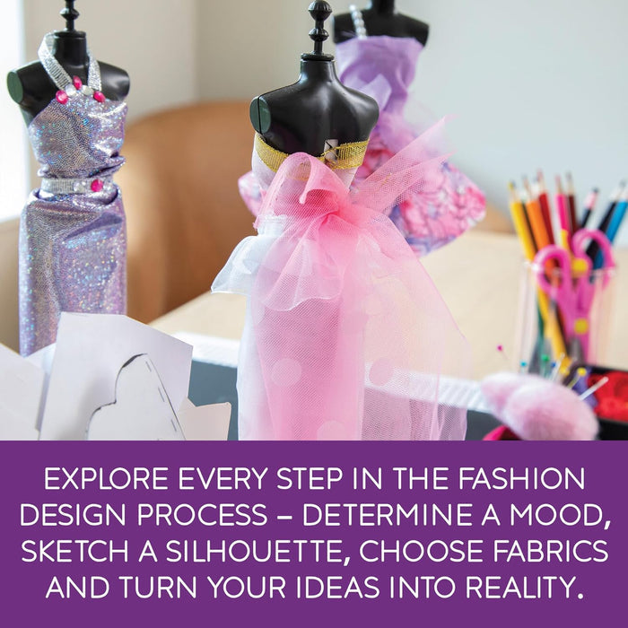 Three mini mannequins dressed in sparkly purple and pink tulle next to fashion design tools, pencils, and sketches.