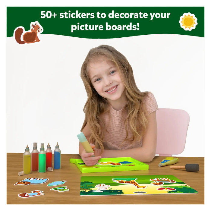 Child creating animal sand art with colorful sand bottles, stickers, and a jungle-themed picture board.