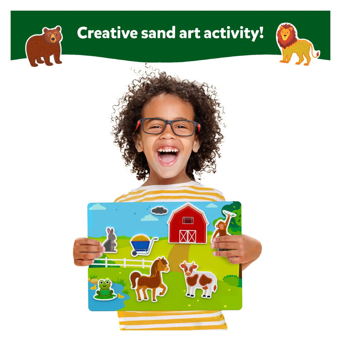 Child holding a farm animal sand art board with a red barn and cow. Top banner says Creative sand art activity!
