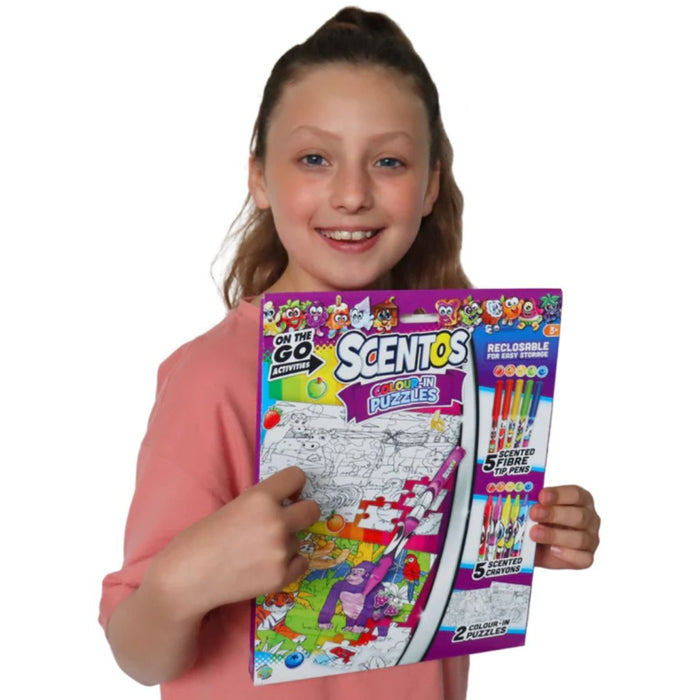 Smiling girl holding a purple Scentos activity pack with jungle animal puzzles, 5 scented pens, and 5 crayons.