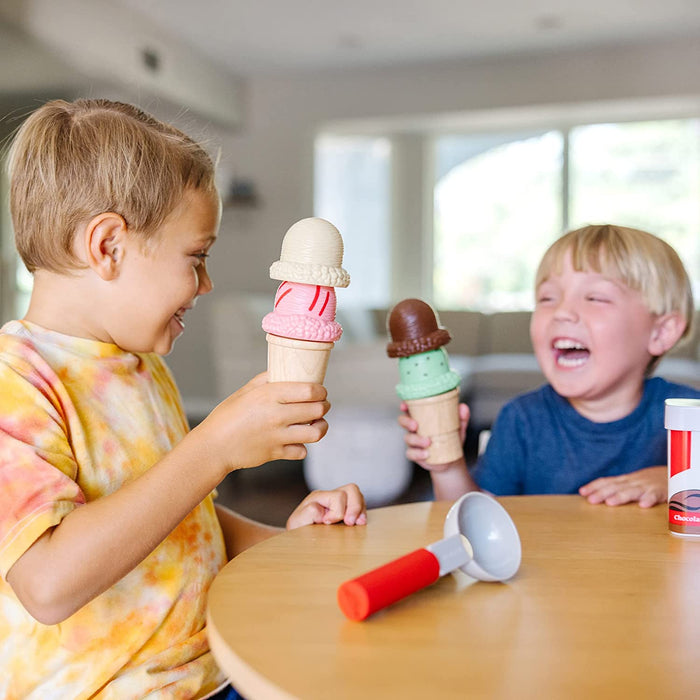 Two boys play with magnetic toy ice cream cones, stacking colorful pink, white, green, and brown scoops with a scooper.