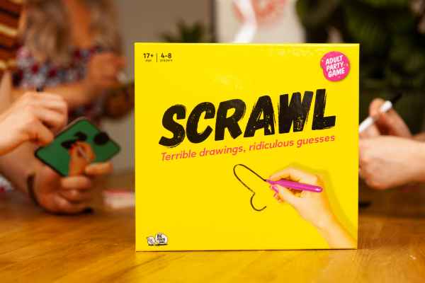 Yellow square box with black SCRAWL text and a hand drawing a suggestive line, shown with people playing at a table.