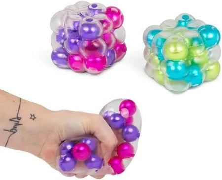 Clear squishy cubes filled with pink, purple, blue, and green beads. A hand squeezes one to show texture.