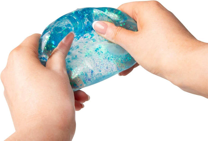 Hands squeezing and stretching a translucent blue squishy sensory toy filled with sparkling iridescent glitter.