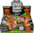 Display box of orange highland cow squishies in clear bags with green clips and cartoon cow graphics.