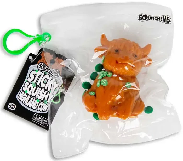 Orange squishy highland cow toy with green leaf accents in a clear plastic bag with a green clip and product tag.