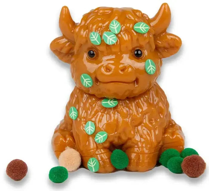 Brown squishy Highland cow toy with green leaf accents and small fuzzy pom-poms around the base.