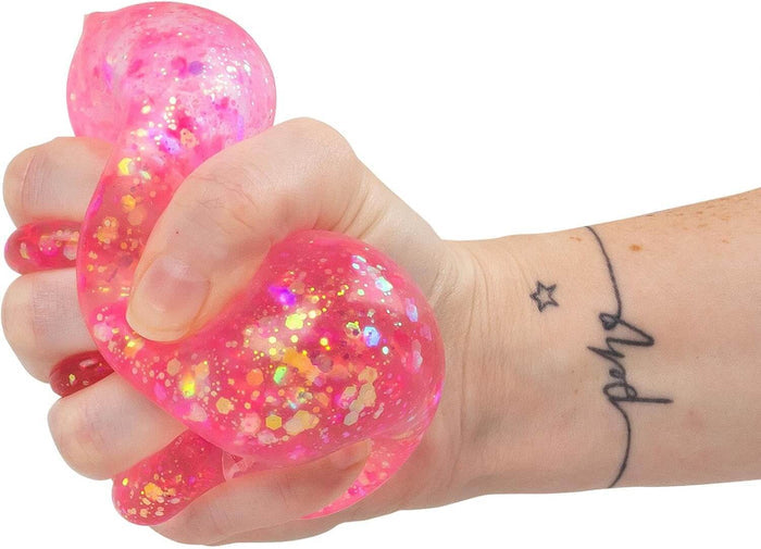 Hand squeezing a pink, translucent flamingo squishy toy filled with sparkling, iridescent glitter.