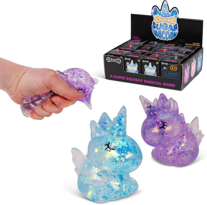 Translucent blue and purple glitter unicorn squishies, one being squeezed, beside a black retail display box.