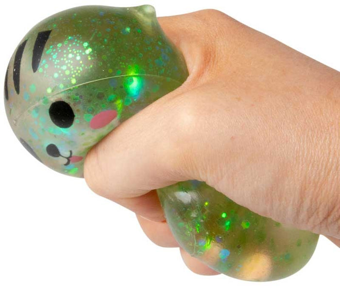 A hand squeezing a translucent green cat-shaped squishy toy filled with sparkling green and iridescent glitter.