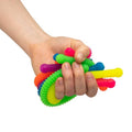 Hand squeezing a bunch of bright, textured stretchy noodles with bumpy and ribbed patterns in multiple colors.