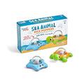 Blue starfish and green turtle toys with dice in clear domes, shown in front of their colorful retail box.