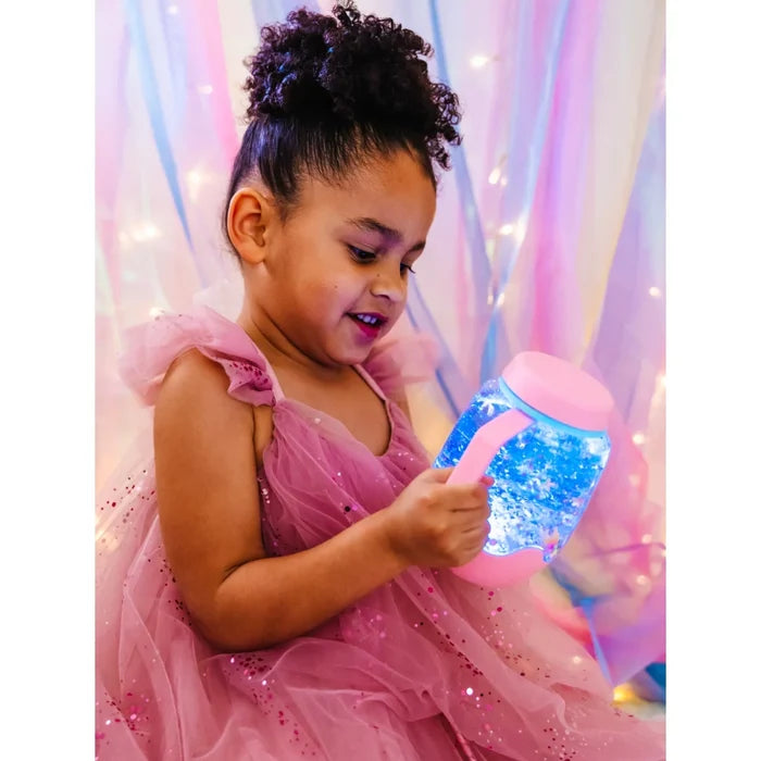 Young girl holding a pink sensory jar filled with glowing blue light and sparkling glitter.