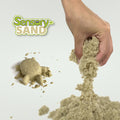 Tan sensory sand squeezed by a hand next to a molded sand turtle and a Sensory Sand brand logo.