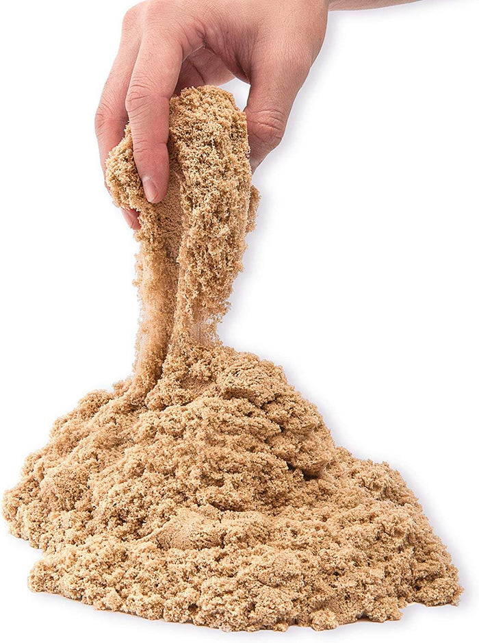 Hand lifting tan sand to show its flowing, crumbly texture over a pile against a plain white background.