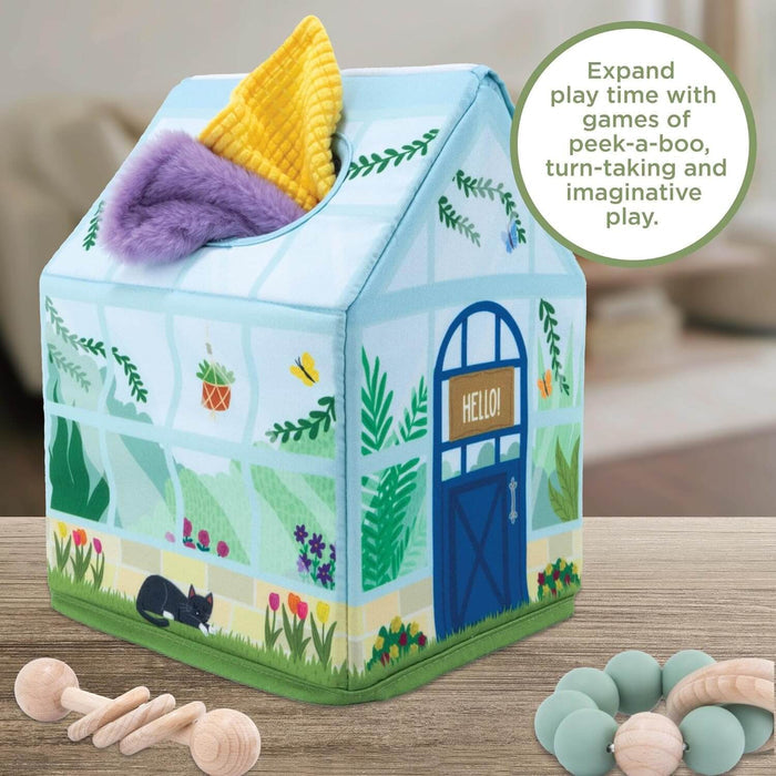 Plush garden-themed house with purple and yellow scarves poking out the top, near wooden baby toys.