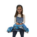 A child sitting with a shimmering blue and silver reversible sequined pad resting on their lap.