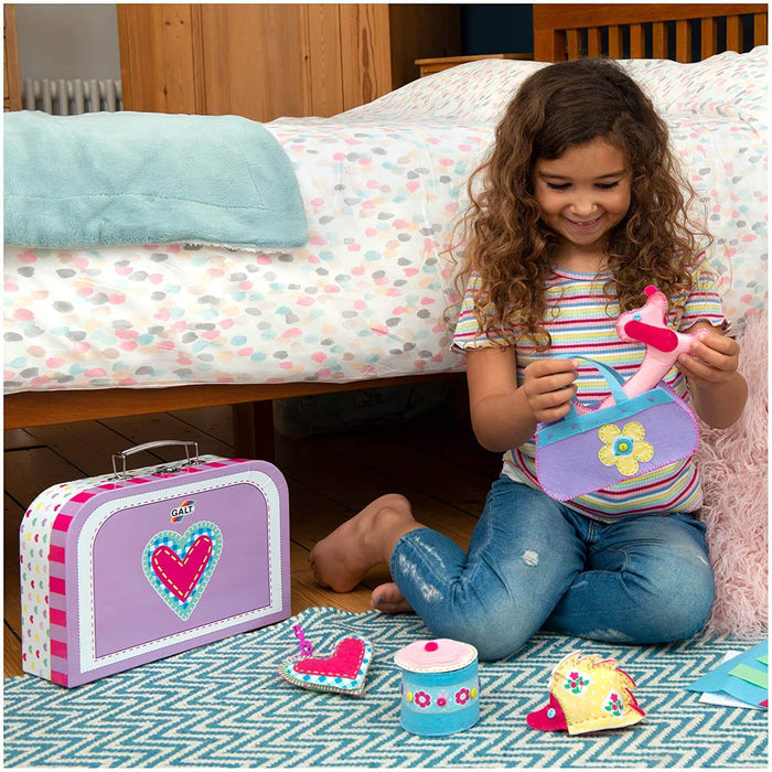 A child plays with felt crafts beside a purple carrying case featuring a heart design and Galt logo.
