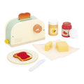 Pastel wooden toy toaster set with jam jars, butter blocks, a decorated plate with toast, and a wooden knife.