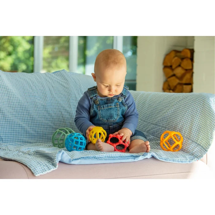 Baby playing with five colorful, flexible, lattice-patterned silicone toy balls on a blue checkered blanket.