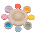 Beige circular silicone teether with colorful pop bubbles and textured sensory tabs around the perimeter.