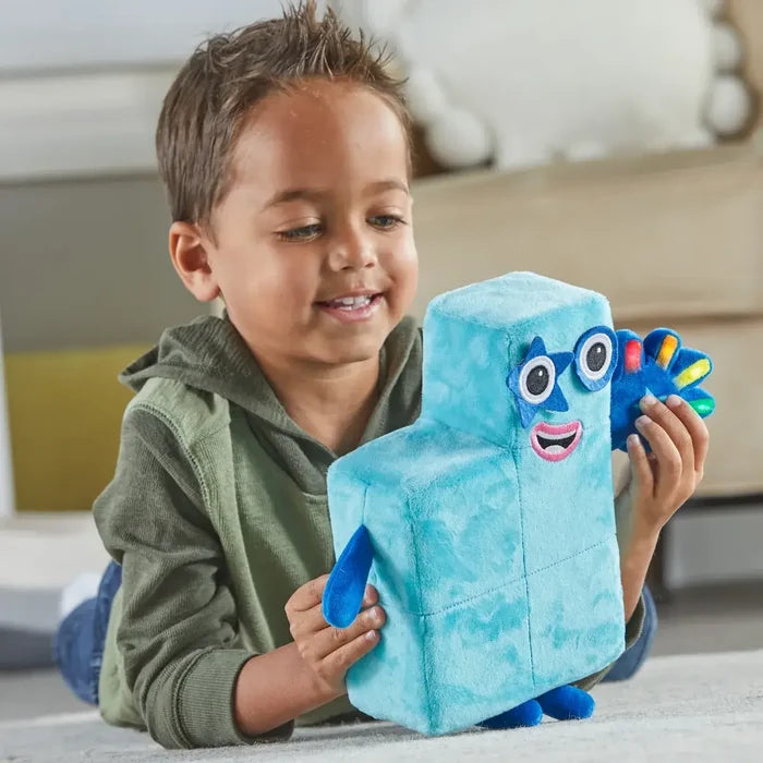 A child plays with a blue five-block plush toy featuring a star-shaped eye and a colorful high-five hand.