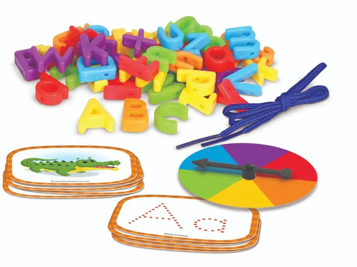 Colorful plastic letters, blue lacing cord, rainbow spinner, and stacks of cards with animal and letter illustrations.
