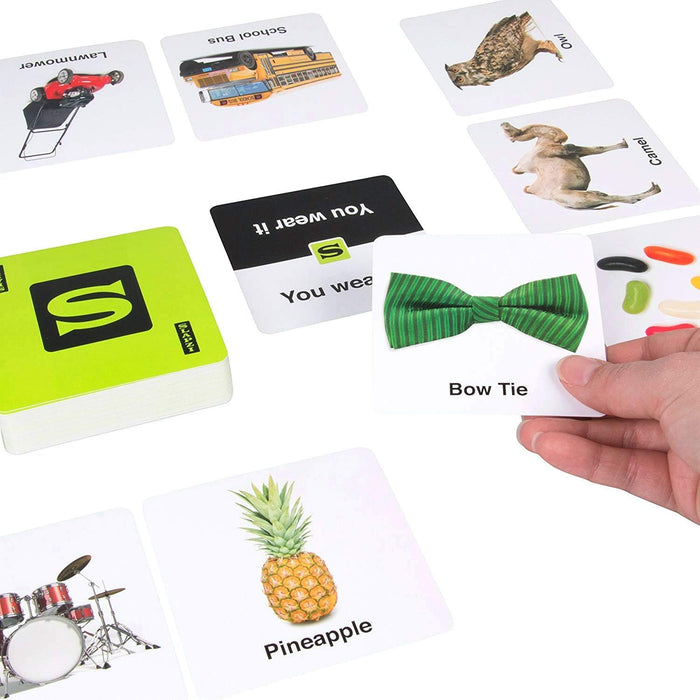 Slapzi card game with a green box and image cards. A hand holds a green bow tie card near a pineapple card.