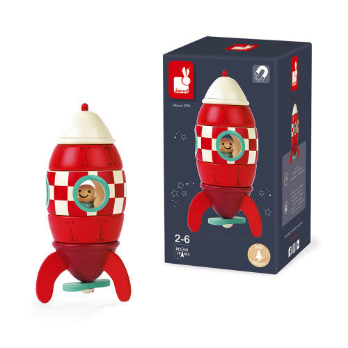 Red and white checkered wooden toy rocket with pilot figure next to its dark blue box packaging.