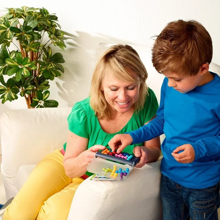 Woman and child play with a blue 3D puzzle case featuring colorful ball-shaped pieces on a white couch.