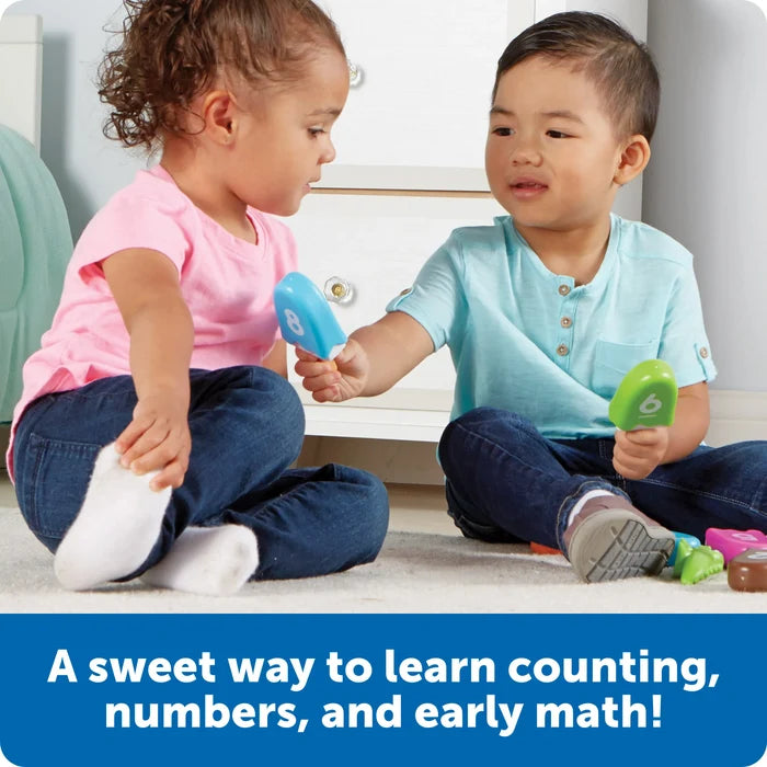 Two children playing with colorful plastic number popsicles, including a blue 8 and a green 6 on a rug.