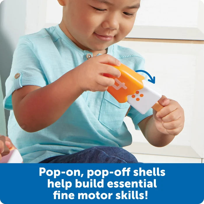 A child fits an orange number 4 shell onto a white popsicle toy base to develop fine motor skills.