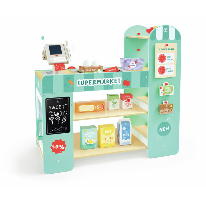 Mint green wooden toy supermarket with a cash register, shelving, and colorful play groceries like milk and eggs.