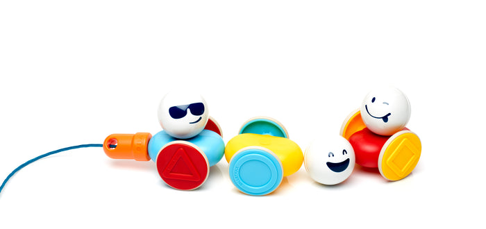 Colorful magnetic toy cars with three white emoji heads, shape-patterned wheels, and an orange pull handle.