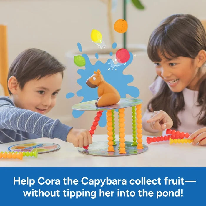 Two smiling kids play a game balancing a capybara on a circular platform supported by colorful, beaded pillars.