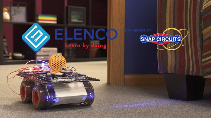 A motorized robot toy with red wheels and blue lights, built with electronic circuit components on a carpeted floor.
