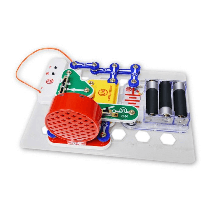 Built FM radio kit with a large red speaker, blue connectors, green switch, and battery pack on a clear grid base.
