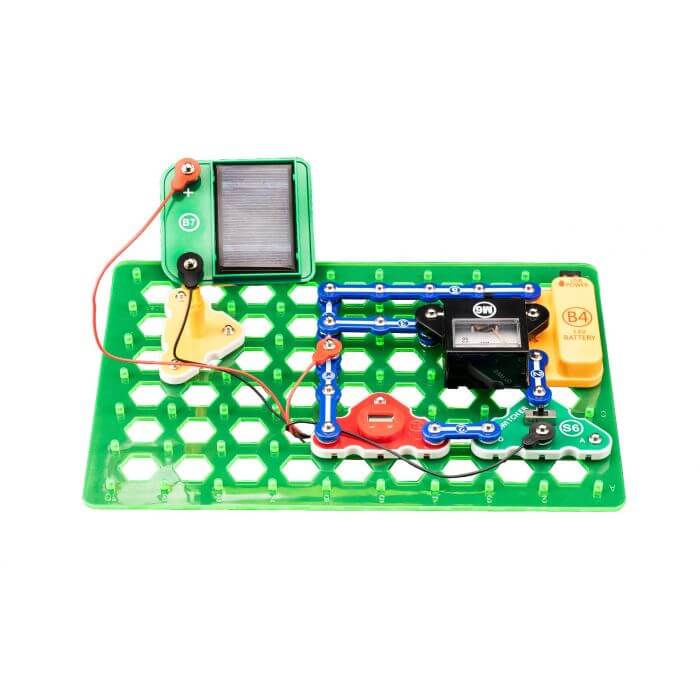 Green electronics kit project with a solar panel, analog meter, and orange battery pack on a hexagonal grid base.