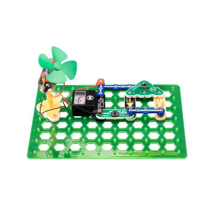 Assembled circuit kit with a four-blade green fan, black ammeter, and blue snap connectors on a green grid base.
