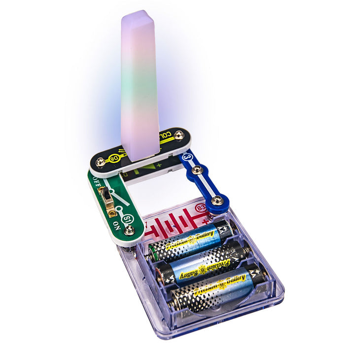 Circuit toy with a green switch and battery pack powering a tall translucent tower glowing purple and green.