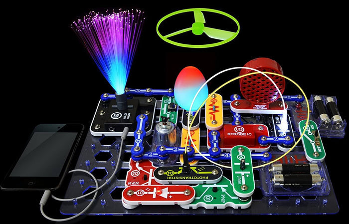 Electronic circuit kit with a glowing fiber optic tree, floating green propeller, and colorful parts on a clear base.