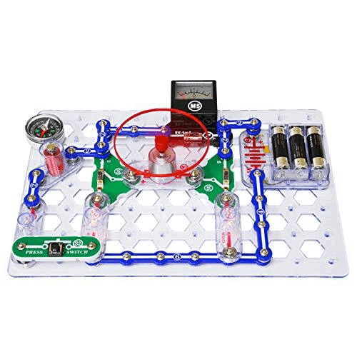 Educational electronics kit with blue connectors, batteries, and a meter. A red circle highlights a central motor.