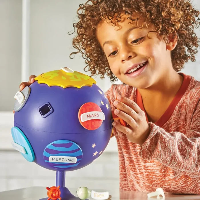 Child playing with a purple globe toy featuring colorful, removable planet pieces and a yellow sun topper.