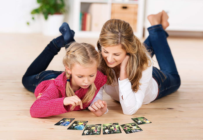 Woman and child lying on a wooden floor looking at a row of small illustrated story sequencing cards.